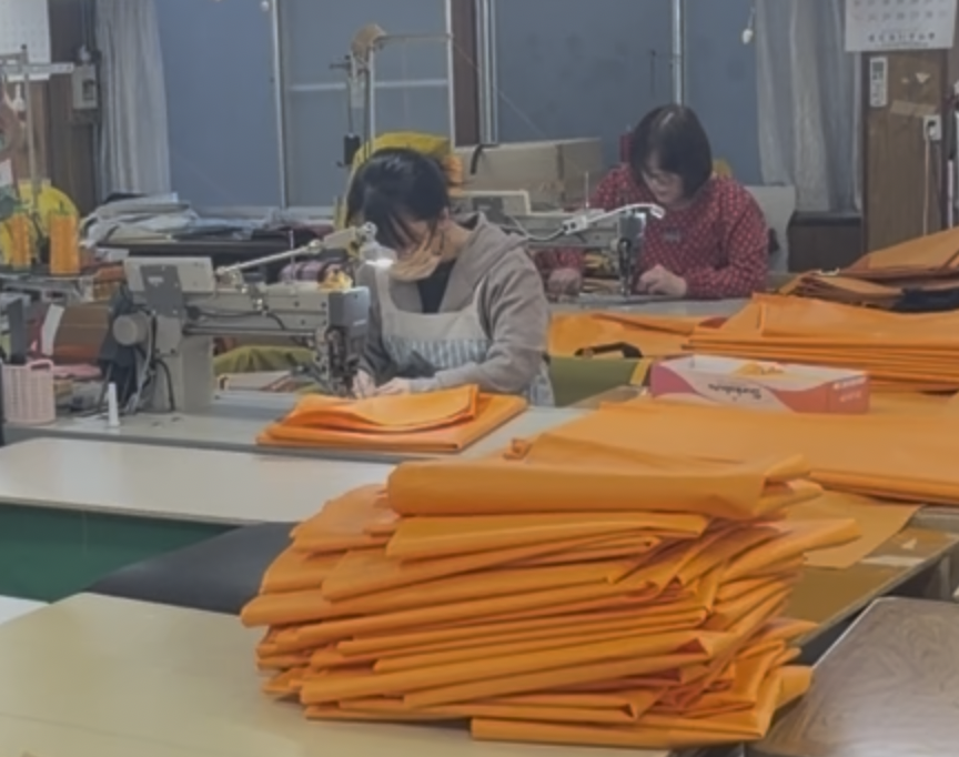 厚手の生地を工業用ミシンで縫製する国内縫製工場の作業風景